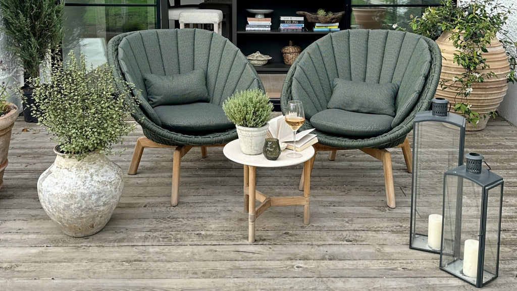 Two outdoor lounge chairs in dark green colour with a small round side table 