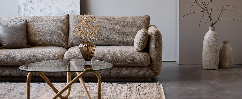 Titelbild des Bloom 3-Sitzer-Sofas im Kimi-Flair-Stoff in der Farbe Taupe mit dem Wave-Couchtisch im Vordergrund