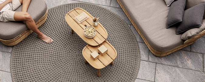 Modernes Lounge-Ambiente mit einem braunen Couchtisch, einem grauen Sofa und beigen Kissen.