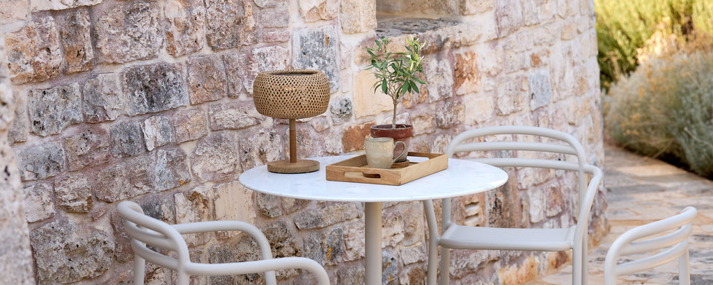 Moderne Außeneinstellung mit weißem Tisch, weißen Stühlen und braunen Dekorelementen.