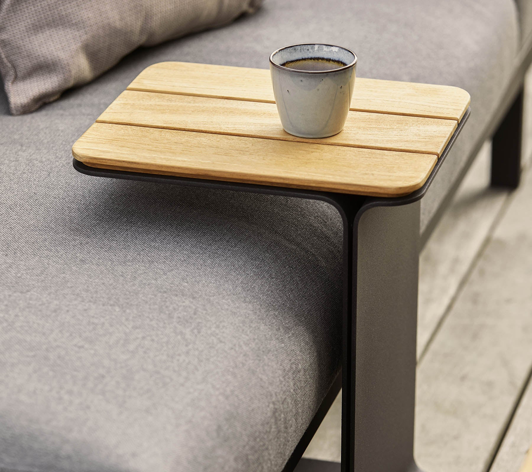 Ein eleganter Beistelltisch mit einer Holzplatte und einem modernen Metallrahmen, auf dem eine kleine Tasse steht.