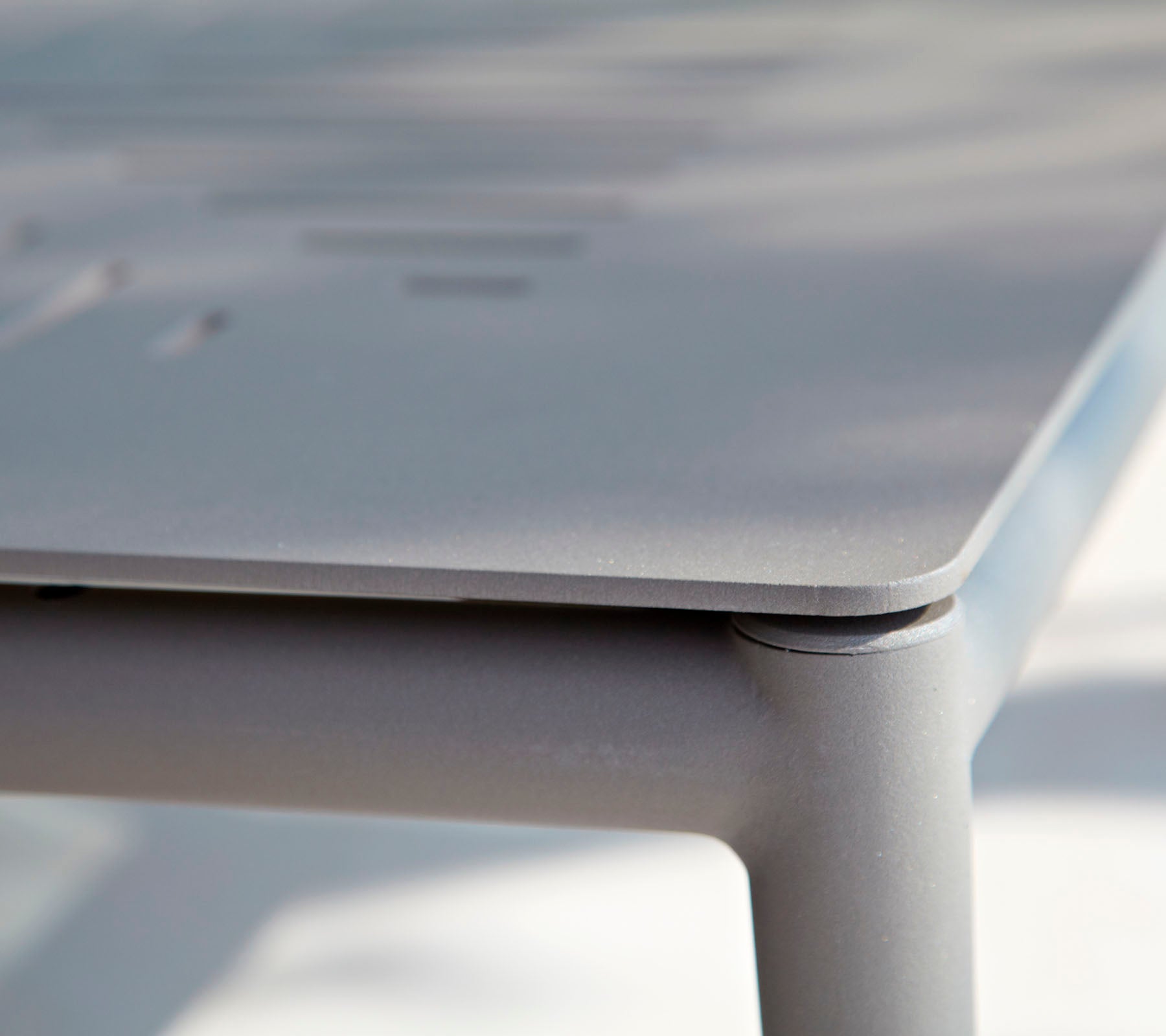 Nahaufnahme eines schlanken, modernen Tisches mit einer glatten Oberfläche und subtilen Details. Das Design betont klare Linien und minimalistischen Stil.
