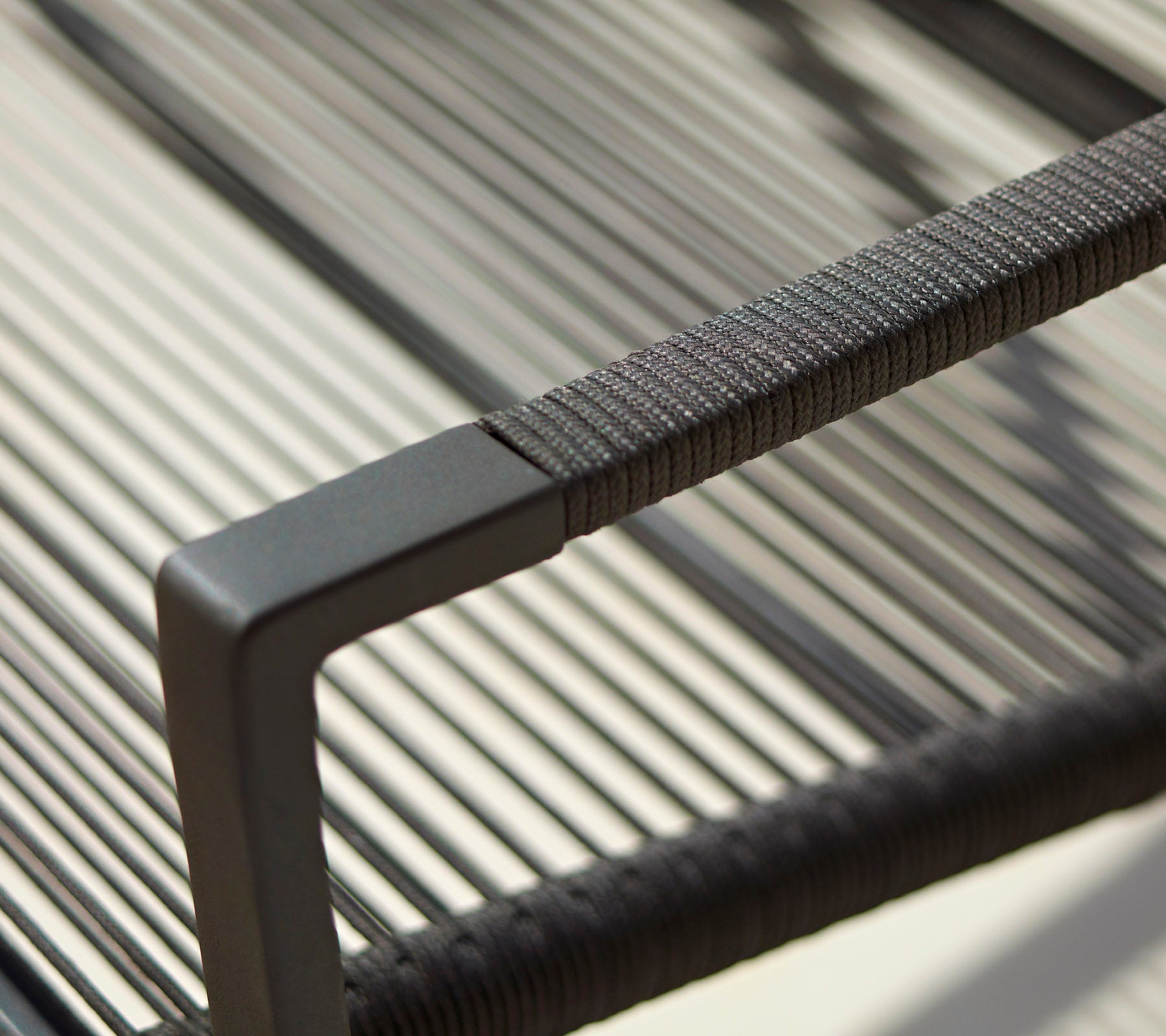 Nahaufnahme einer modernen Stuhlarmlage mit einem schlanken Design, strukturierten Details und einem minimalistischen schwarzen Finish.