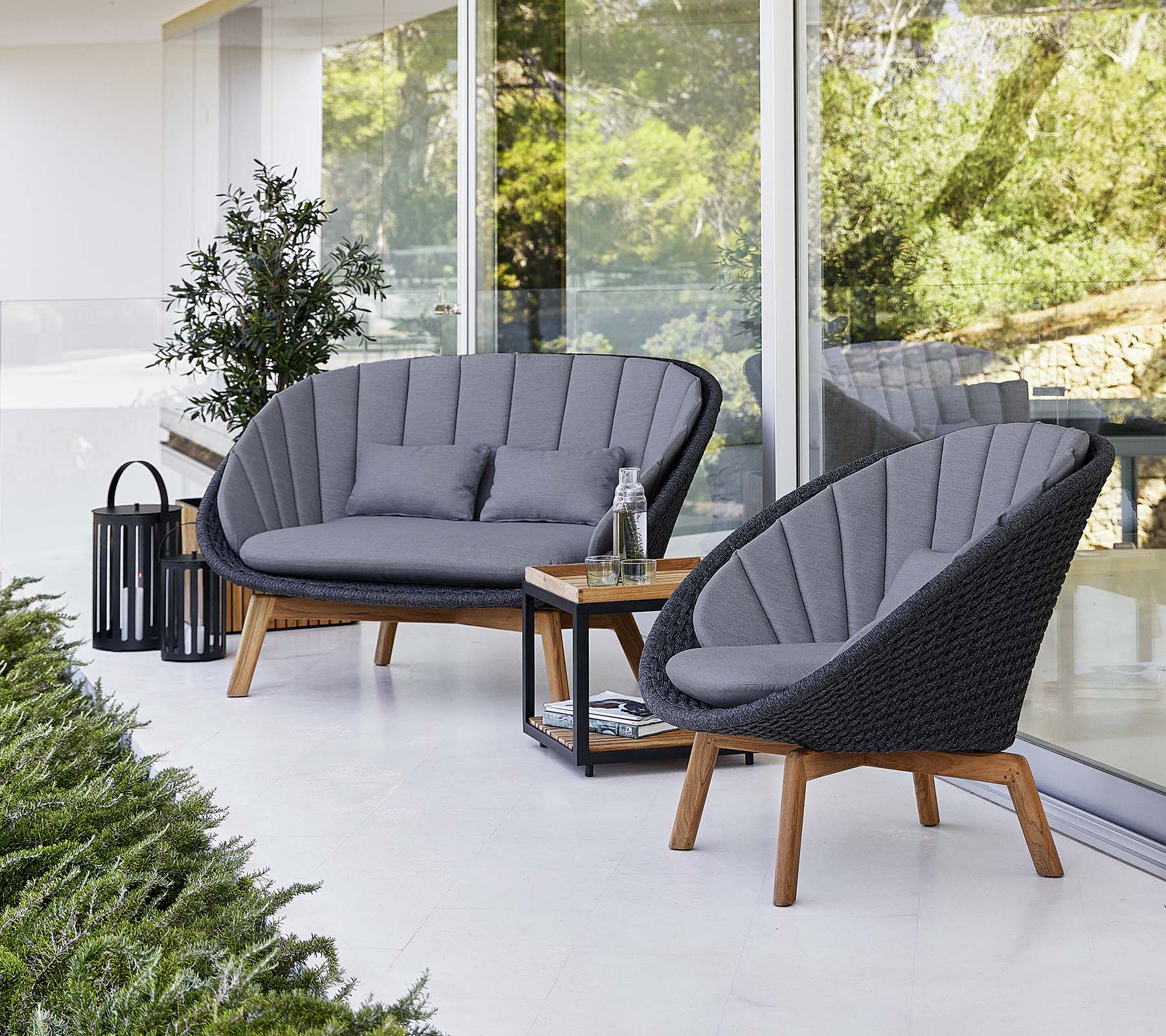 Stylische Außensitzgelegenheiten mit zwei gepolsterten Stühlen und einem Loveseat, begleitet von einem kleinen Tisch und einer dekorativen Laterne.