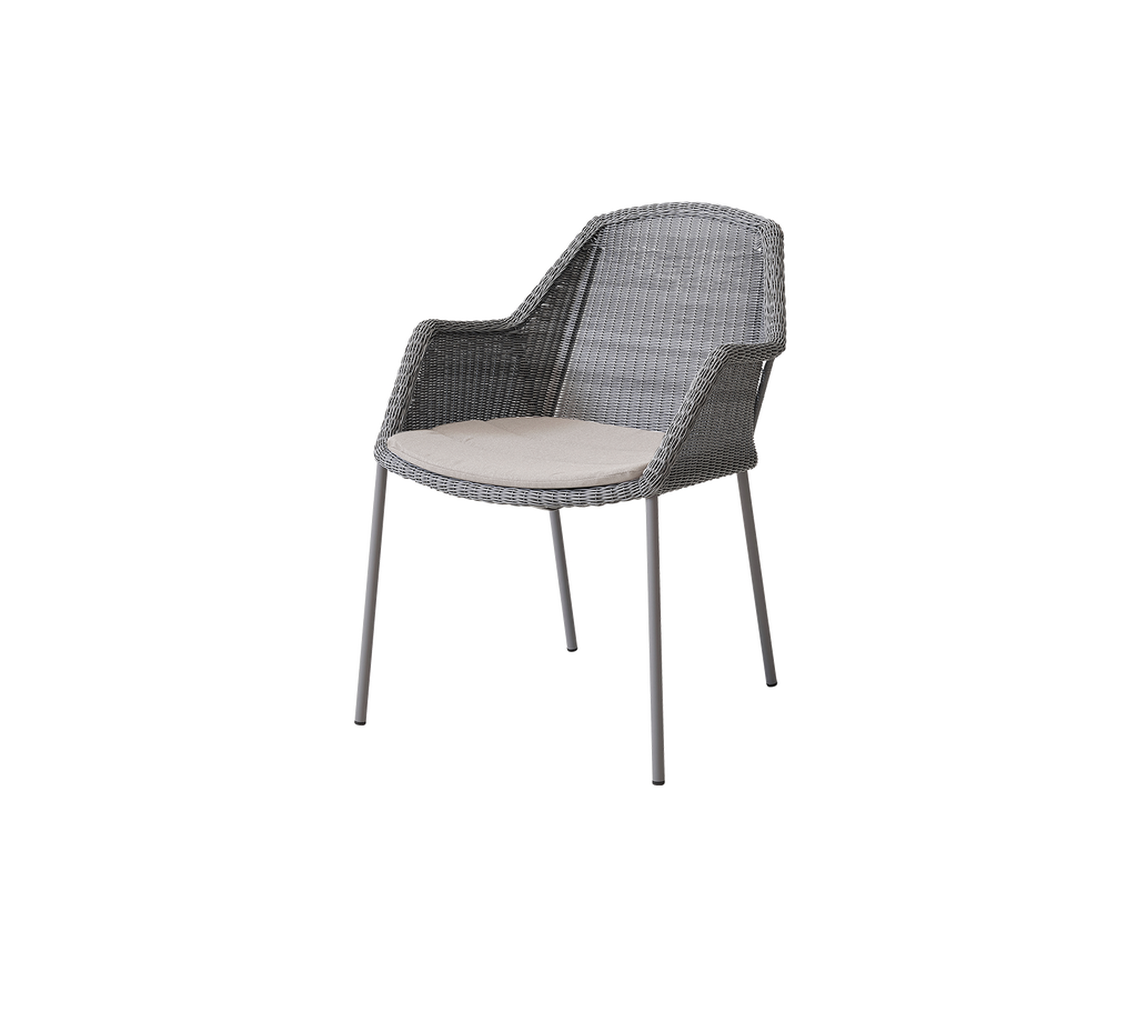 Grau geflochtener Stuhl mit Armlehnen, ausgestattet mit einem hellen Kissen in einem minimalistischen Design, geeignet für den Innen- oder Außenbereich.