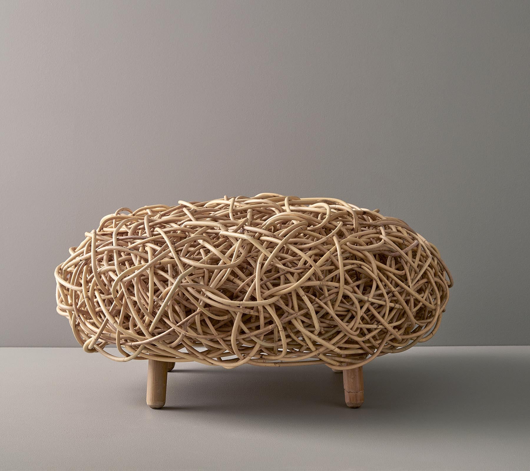 Natürlich geflochtenes dekoratives Stück in ovaler Form, mit intricaten verflochtenen Strängen und unterstützt von kurzen Holzbeinen.