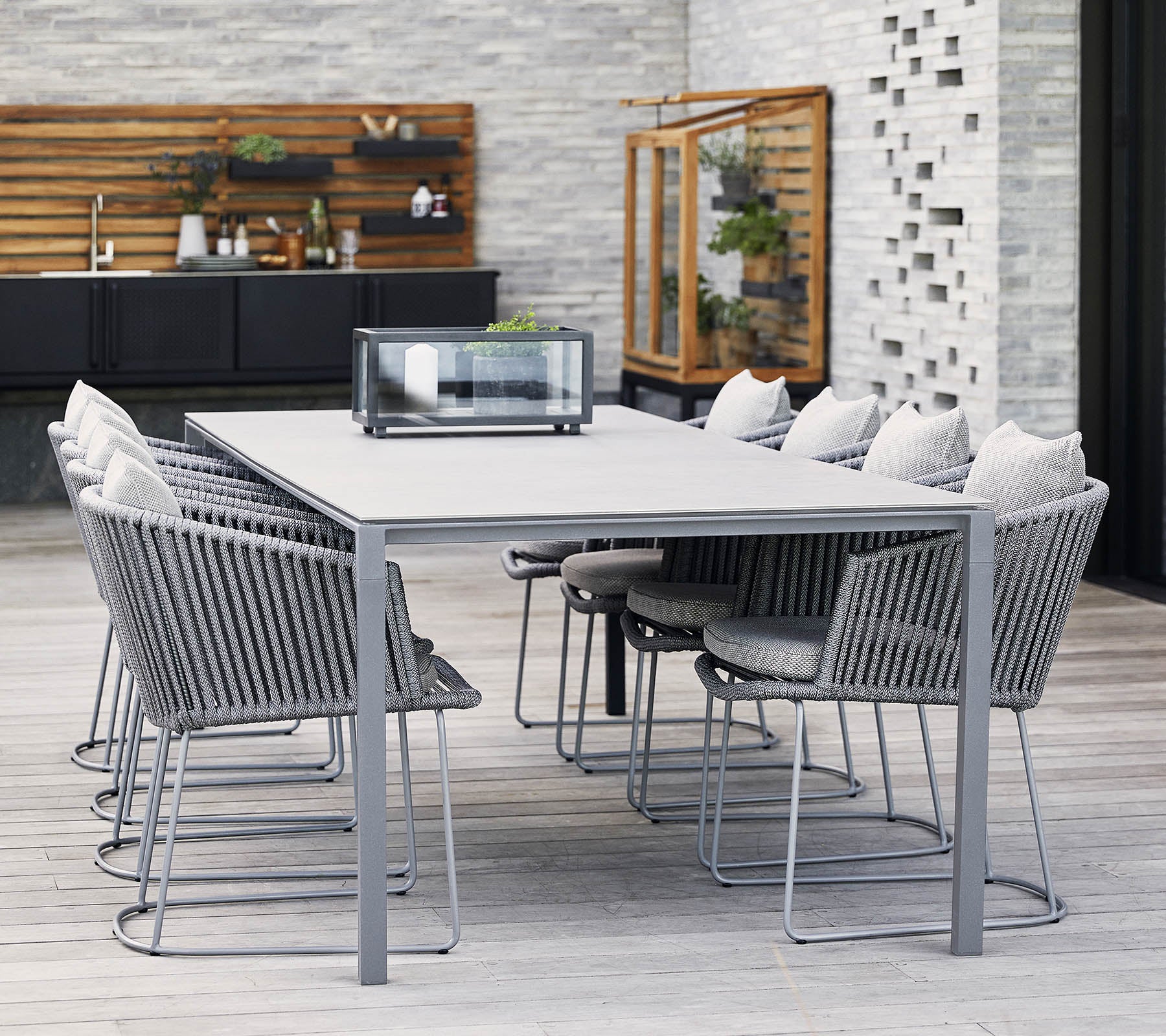 Ein moderner Esstisch mit grauem Metallrahmen und bequemen Stühlen, ausgestattet mit weichen Kissen und einem minimalistischen Design, ideal für Zusammenkünfte.