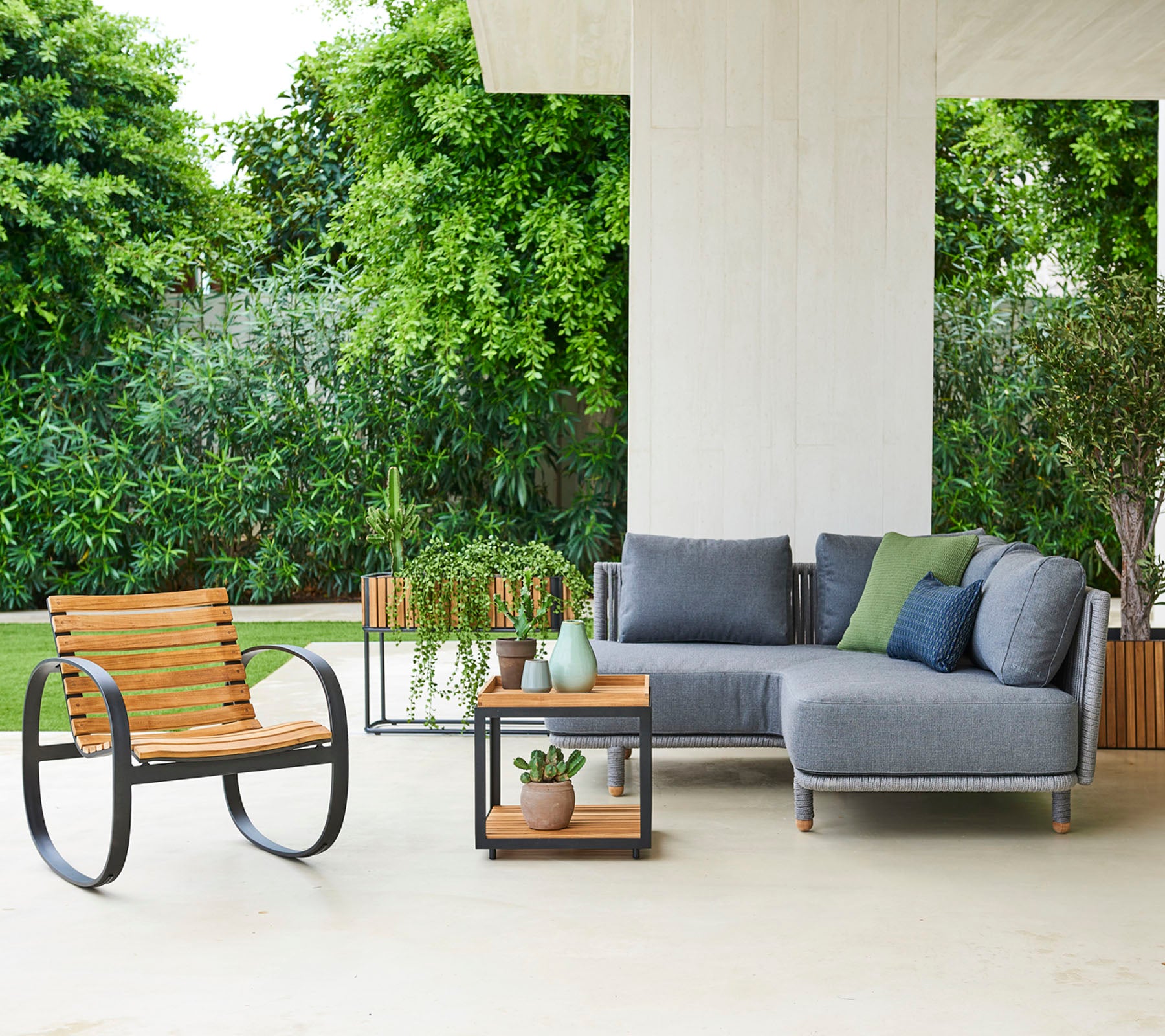 Zeitgemäße Sitzanordnung mit einem modularen Sofa mit Kissen, einem stilvollen Stuhl und einem Beistelltisch mit dekorativen Pflanzen.