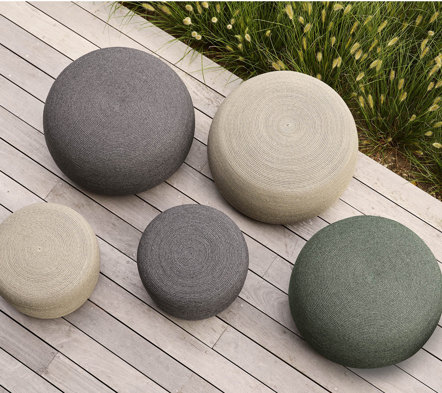 Ein Set aus fünf runden Poufs in verschiedenen Größen und Farben, mit strukturierten Oberflächen, die jedem Raum einen modernen Touch verleihen.