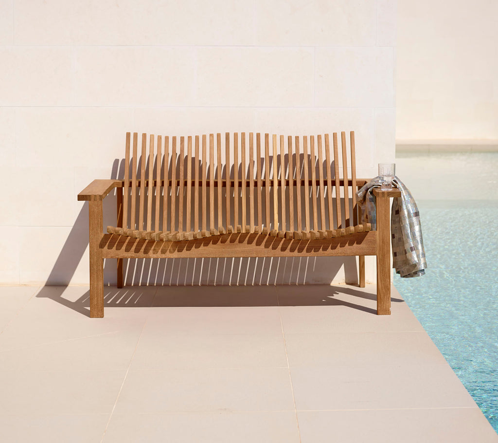 Stylische Holz-Zweisitzer-Sofa mit Latten-Design, ergänzt durch eine gemütliche Decke, neben einem ruhigen Pool. Perfekt zum Entspannen.