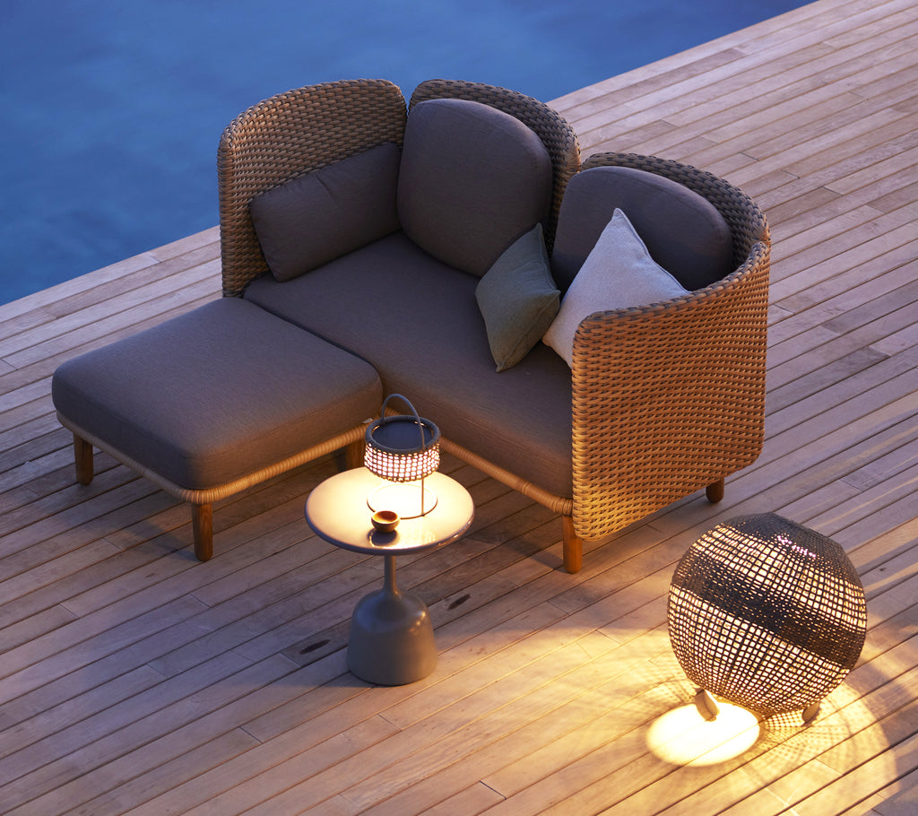 Gemütliches 2-Sitzer-Sofa mit niedriger Rückenlehne, begleitet von einem kleinen Beistelltisch und einer dekorativen Laterne. Perfekt zum Entspannen.