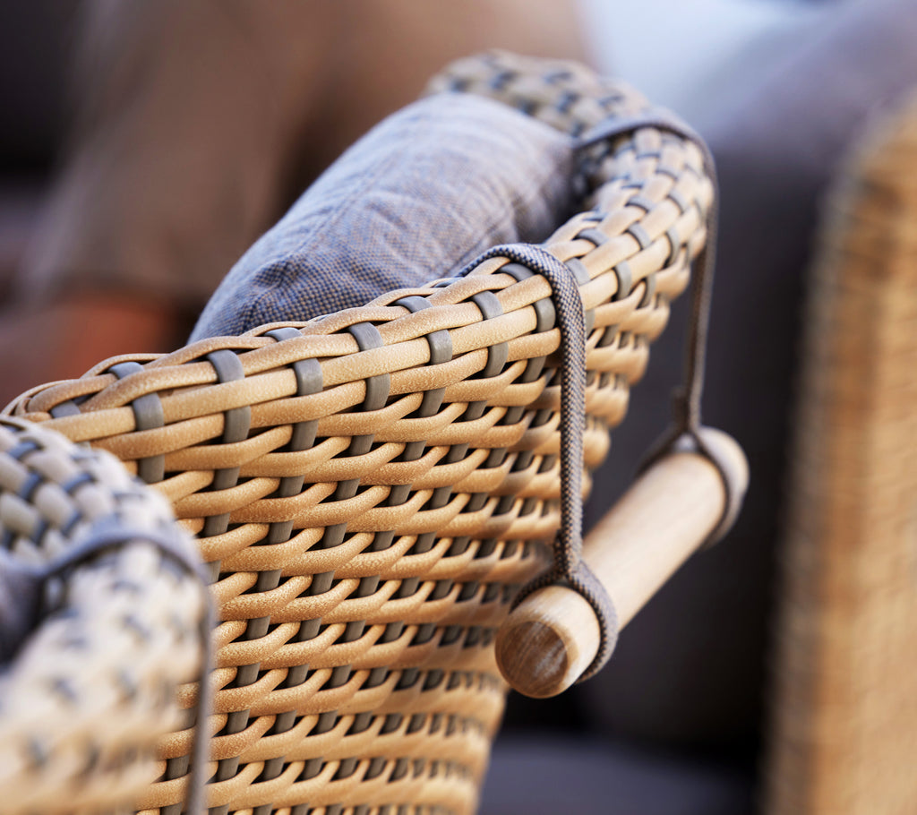 Nahaufnahme einer geflochtenen Stuhlarmlehne mit gepolsterter Rückenlehne und gewölbter Nackenstütze für zusätzlichen Komfort.