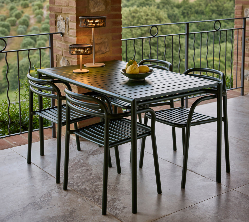 Ein stilvolles Esszimmer-Set mit einem eleganten Tisch, vier Stühlen und einer eleganten Lampe, ergänzt durch eine dekorative Obstschale.