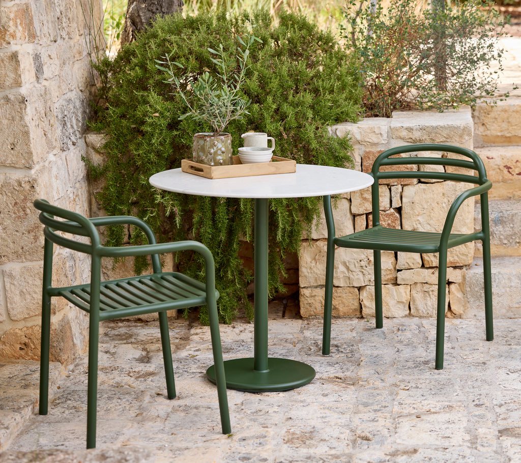 Moderne Außenbereich mit grünen Stühlen und einem weißen Tisch.