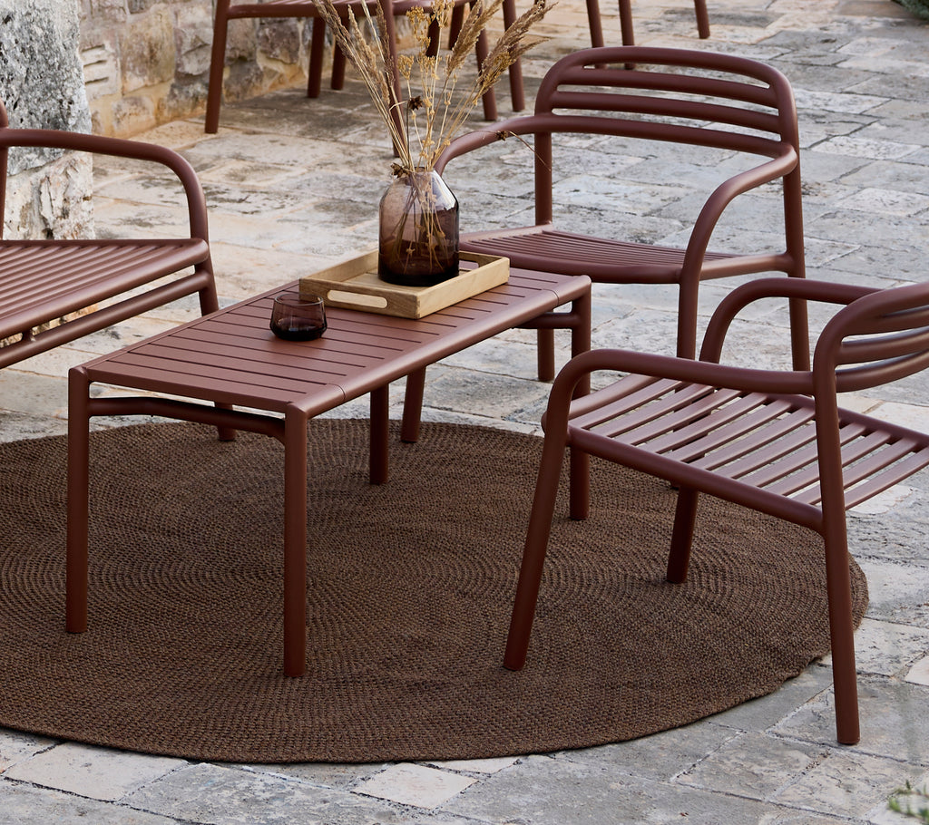 Minimalistischer brauner Tisch und Stühle in einer Lounge-Umgebung angeordnet.