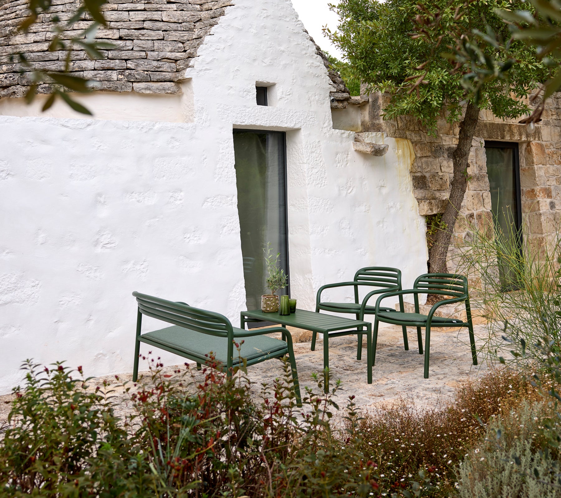 Grüne Gartensofa und Sessel mit einem Couchtisch in einer gemütlichen Umgebung.