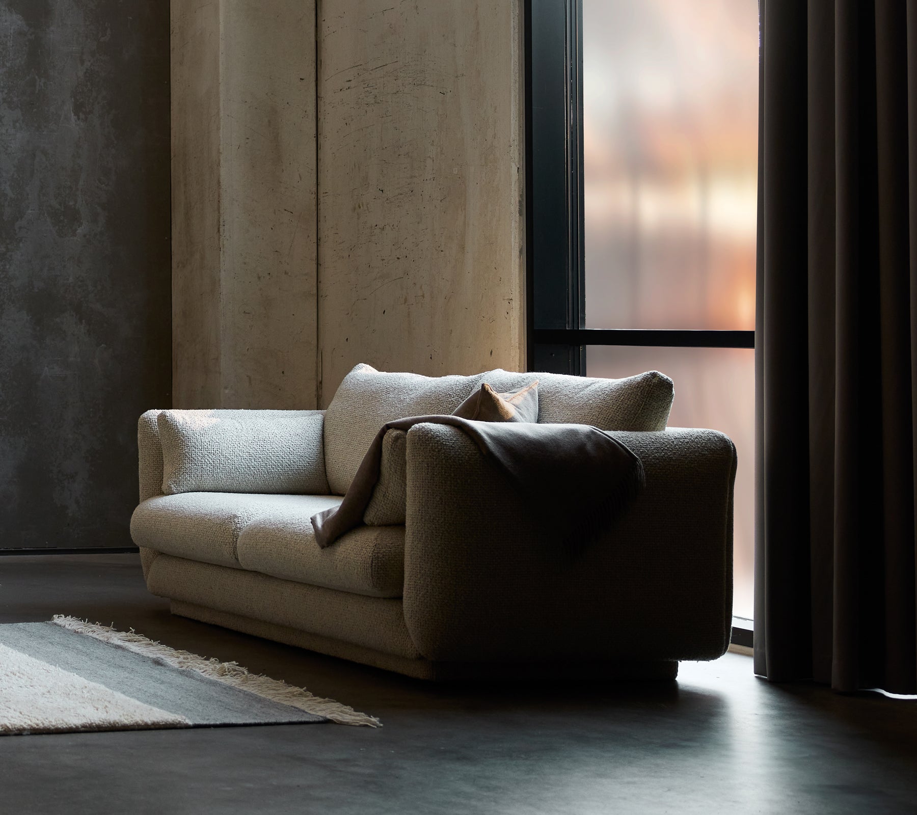 Bloom 2-Sitzer Sofa in Sand Flair, mit einem Sockel-Design und einer gemütlichen Decke, die über eine Seite drapiert ist.