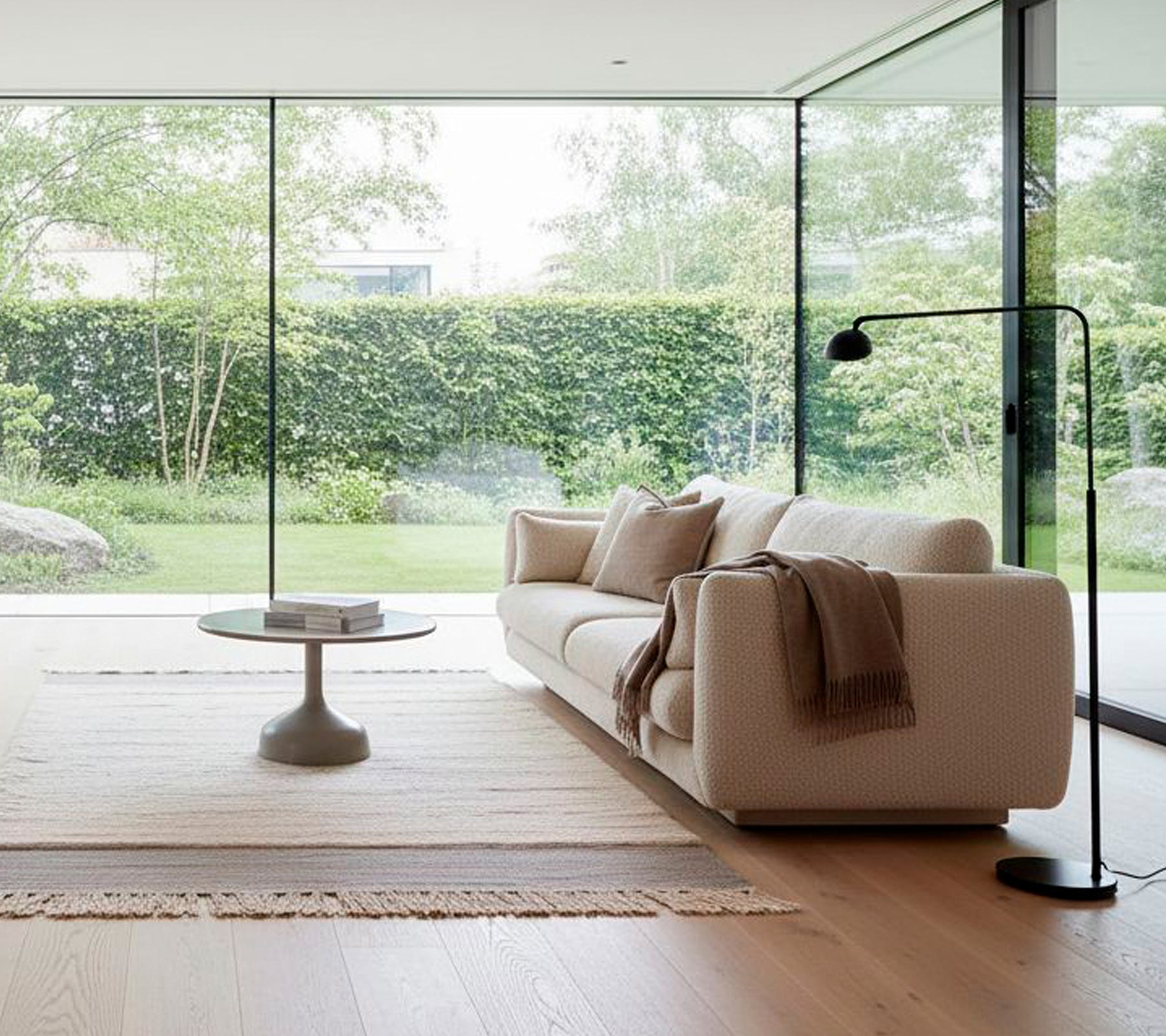 Modernes weißes Sofa mit einer schwarzen Stehlampe und einem runden Couchtisch in einem minimalistischen Wohnzimmer.