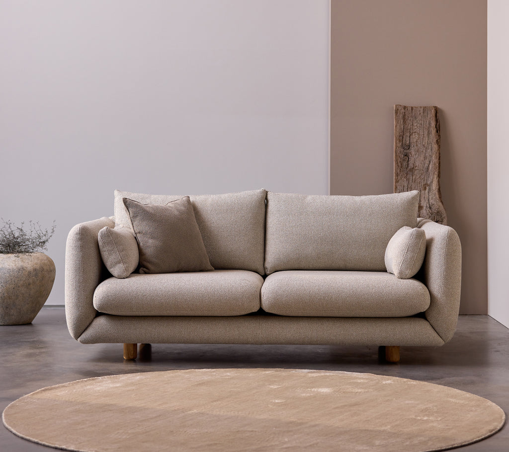 Bloom 2-Sitzer Sofa mit Teakholzbeinen in der Farbe Desert Sand, ausgestattet mit kuscheligen Kissen und einem weichen, minimalistischen Design.