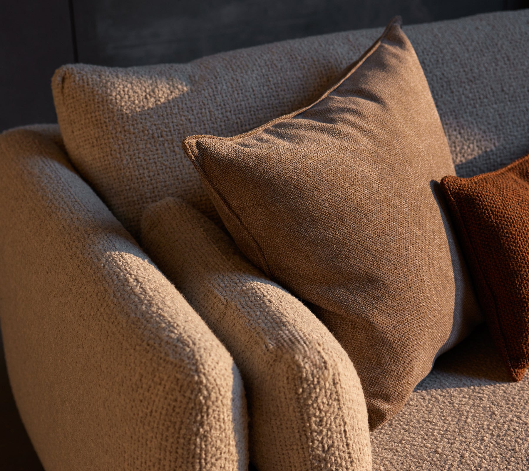 Gemütliches Ecksofa mit strukturiertem Gewebe und Essence-Kissen in warmen Farbtönen, die Komfort und Stil in den Raum bringen.