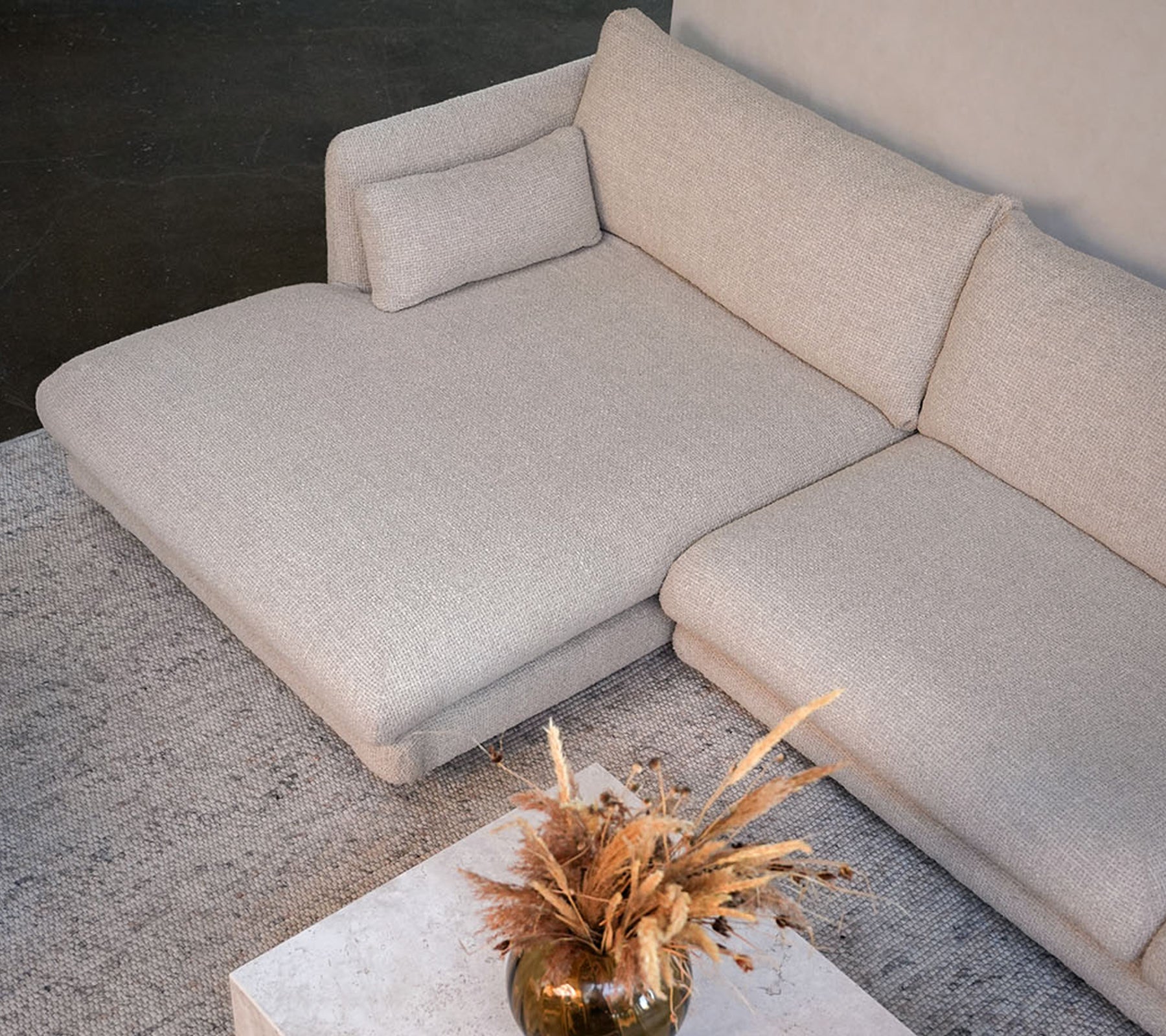 Modernes beiges Sofa mit einem weißen Tisch und einer dekorativen Vase in einem stilvollen Loungedesign.