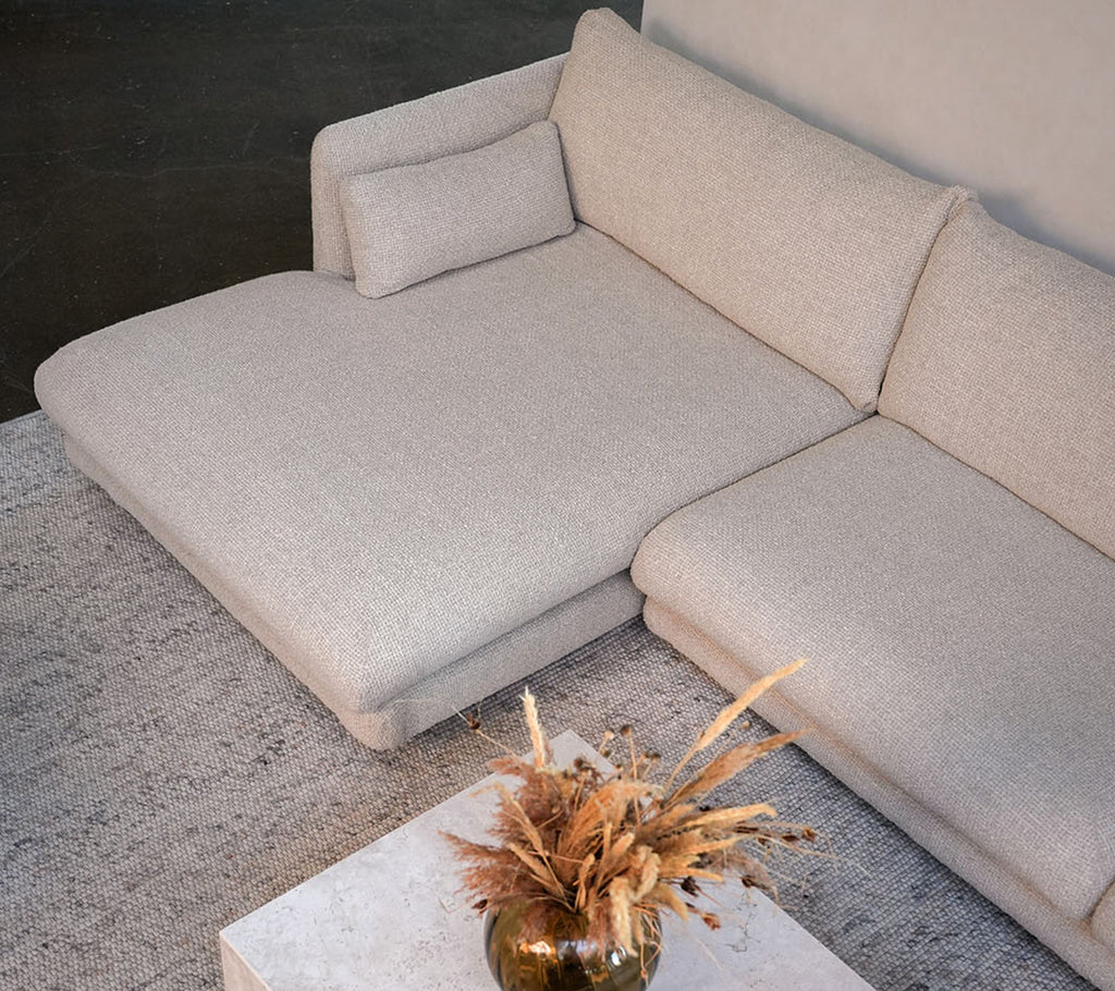 Modernes beiges Sofa mit einem weißen Tisch und einer dekorativen Vase in einem stilvollen Loungedesign.