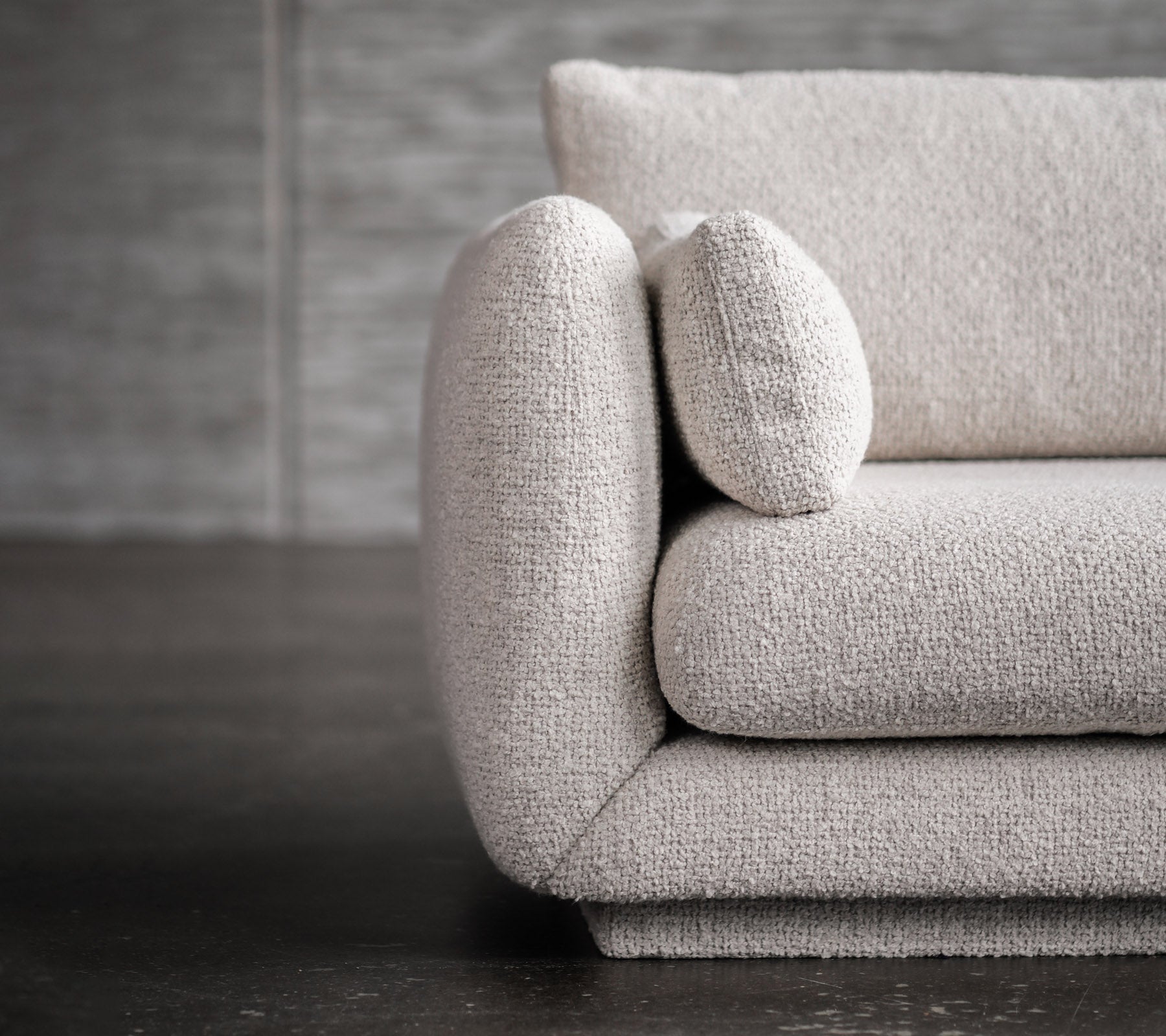 Modernes hellgraues Sofa mit abgerundeten Armlehnen und Kissenakzenten.