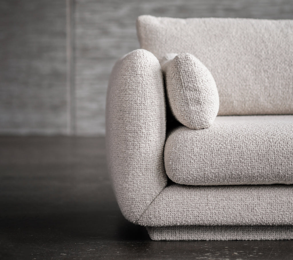 Modernes hellgraues Sofa mit abgerundeten Armlehnen und Kissenakzenten.