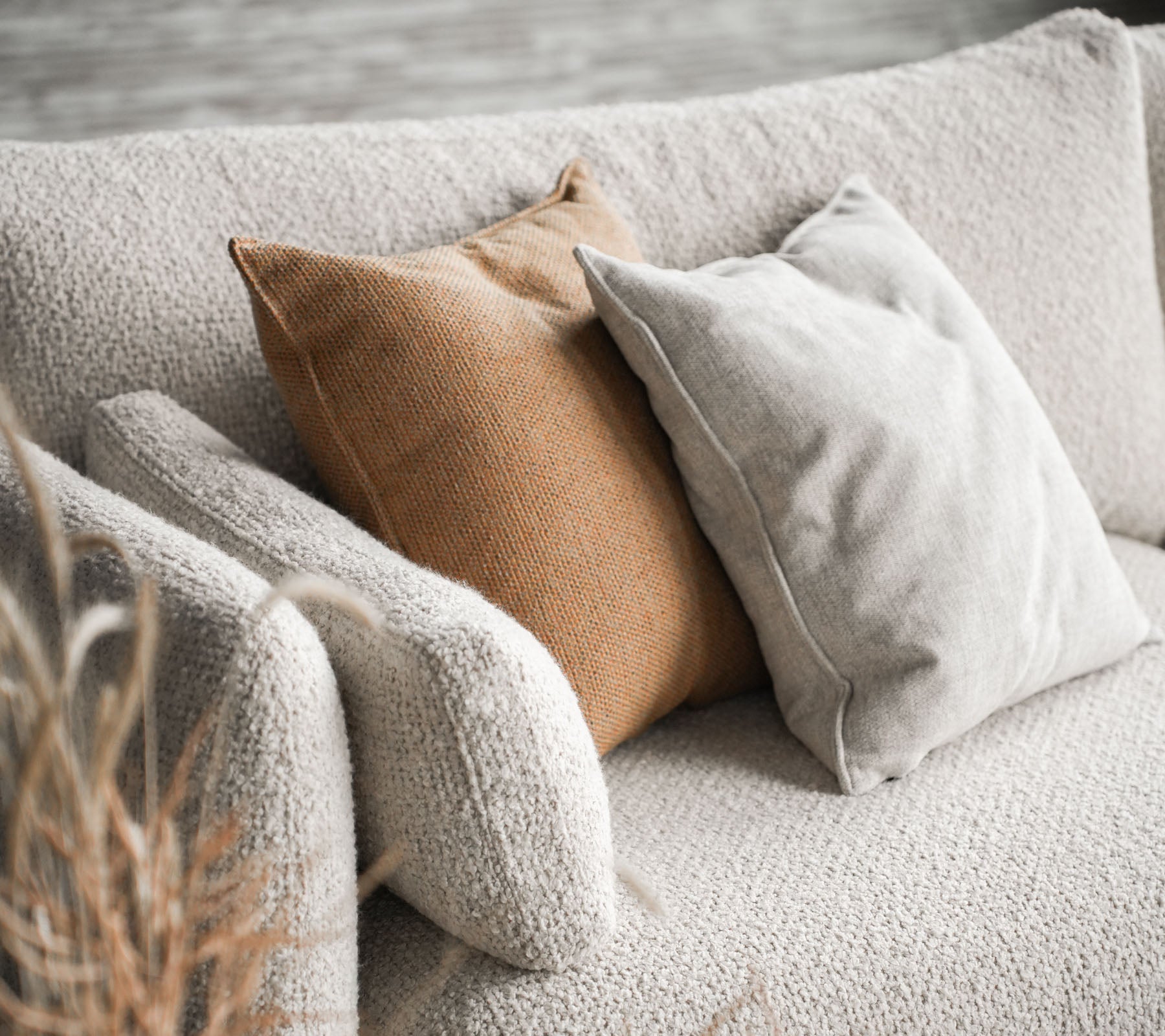 Gemütliches Sofa mit Bloom in Sandfarbe und zwei Kissen, eines in Beige und das andere in warmem Braun, die einen stilvollen Akzent setzen.