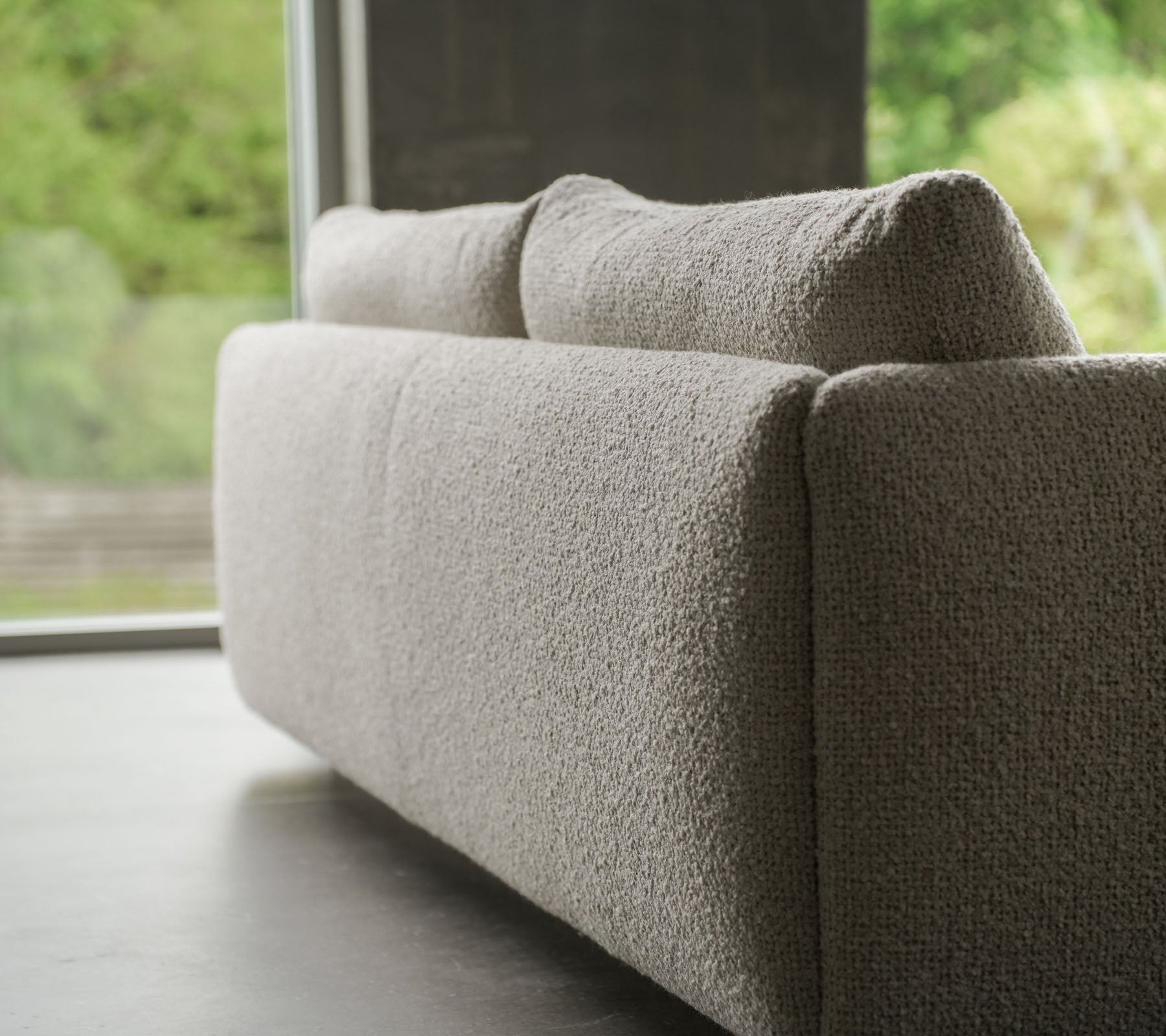 Zeitgenössisches Sofa mit einem strukturierten sandfarbenen Stoff, akzentuiert durch elegante Teakbeine, das Cane-line Flair und weiche Kissen zeigt.