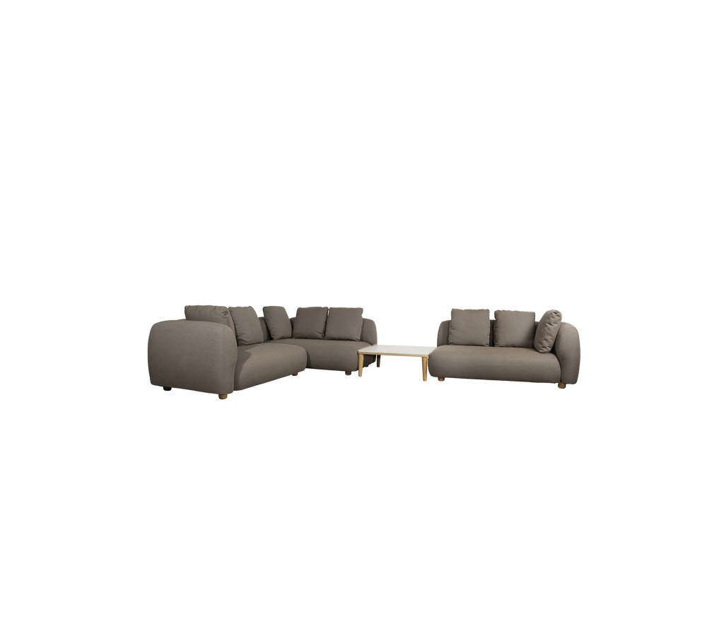 Moderne taupe Sofa mit Kissen und einem hellen Tisch in einer Lounge-Umgebung.