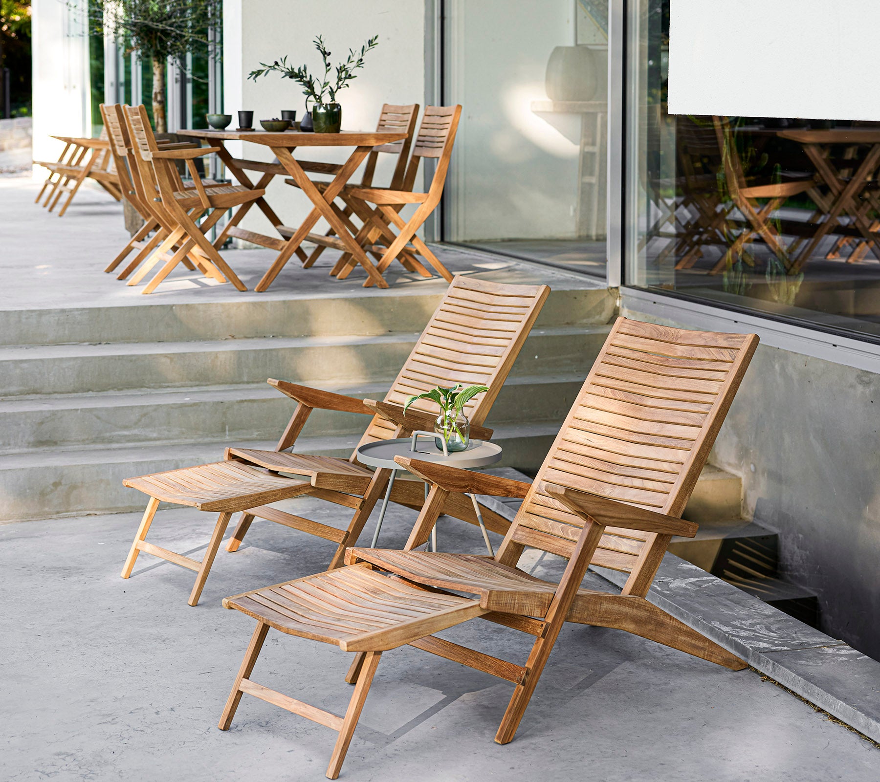 Stylisches Holzmöbel-Set mit Liegestühlen, einem Beistelltisch und einem Esstisch, perfekt für gemütliche Zusammenkünfte und Entspannung.