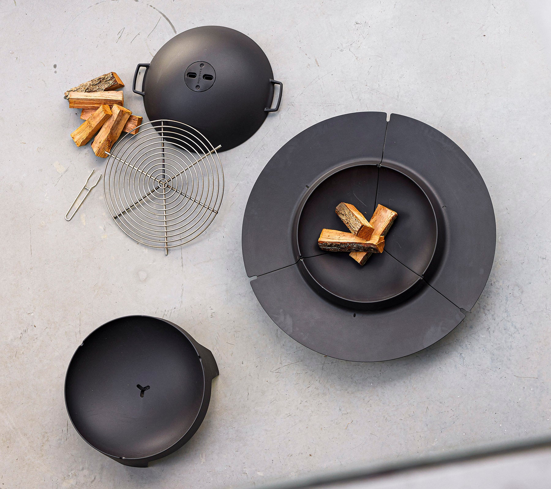 Schwarze Kochgeräte mit Feuerholz und einem Drahtgrillrost, entworfen für das Grillen im Freien und das Kochen mit Feuer.