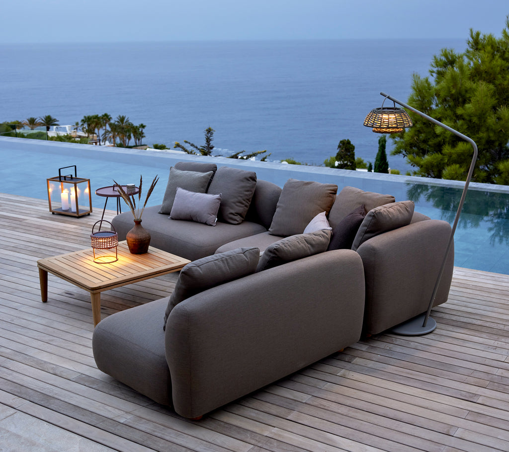 Grau Sofa mit Holztisch und Laternen am Pool mit Blick auf den Ozean.