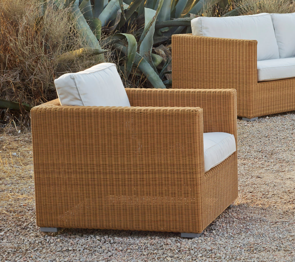 Brauner Sessel mit weißem Kissen in einem modernen Lounge-Ambiente.