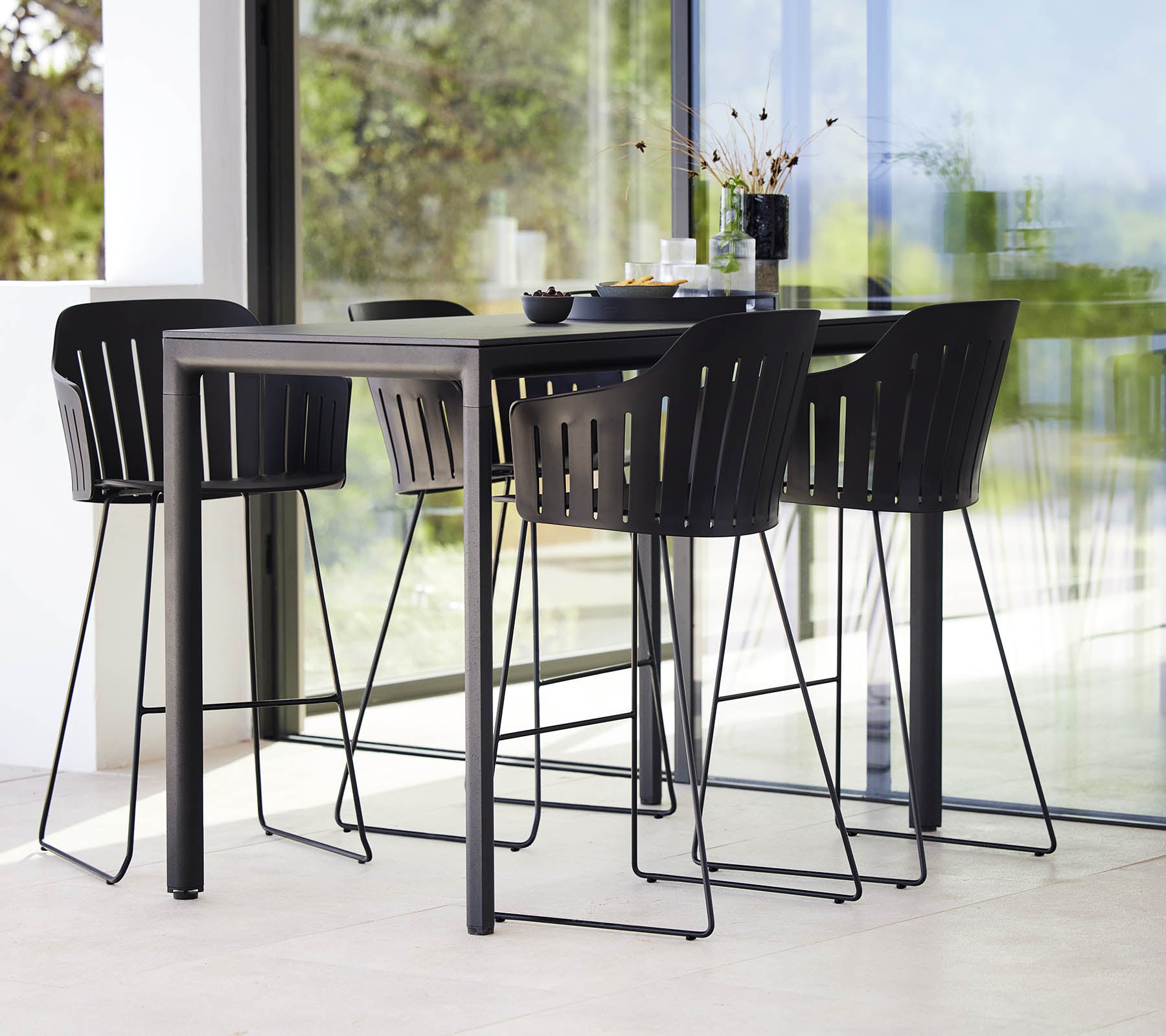 Ein eleganter schwarzer Bartisch kombiniert mit modernen Barhockern mit einem Latten-Design, das eine stilvolle Sitzanordnung schafft.