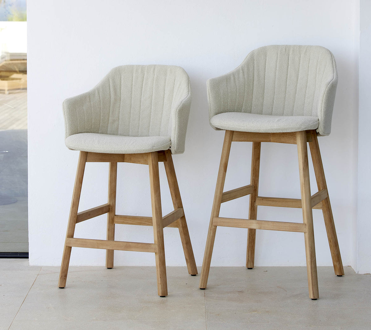 Zwei stilvolle, hellfarbige Stühle mit geschwungenen Rücken und Holzbeinen, die ein modernes und komfortables Design präsentieren.