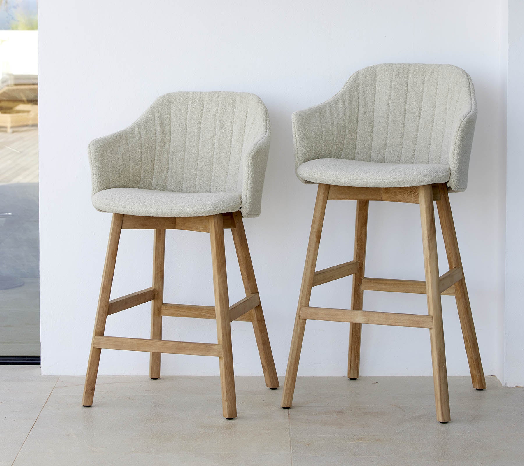 Zwei stilvolle, hellfarbige Stühle mit geschwungenen Rücken und Holzbeinen, die ein modernes und komfortables Design präsentieren.