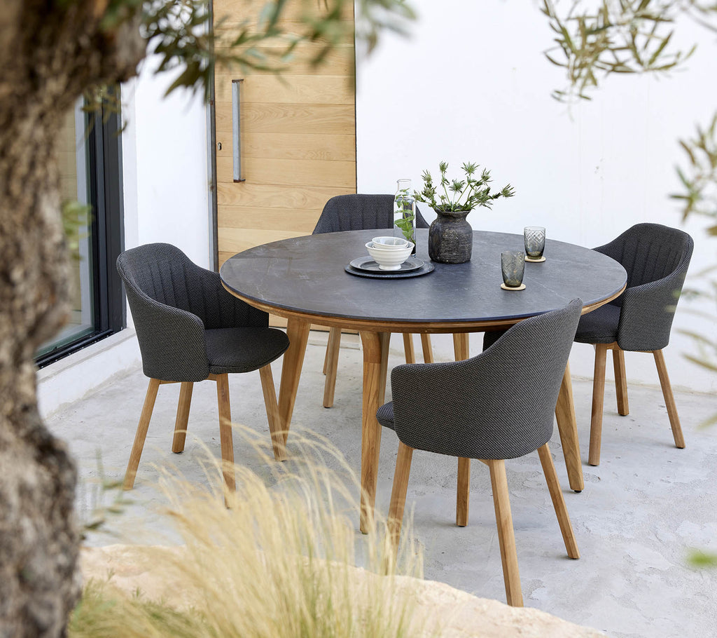 Ein runder Tisch, umgeben von vier stilvollen Stühlen, mit einem Blumenmittelstück und einer einfachen Tischdekoration.