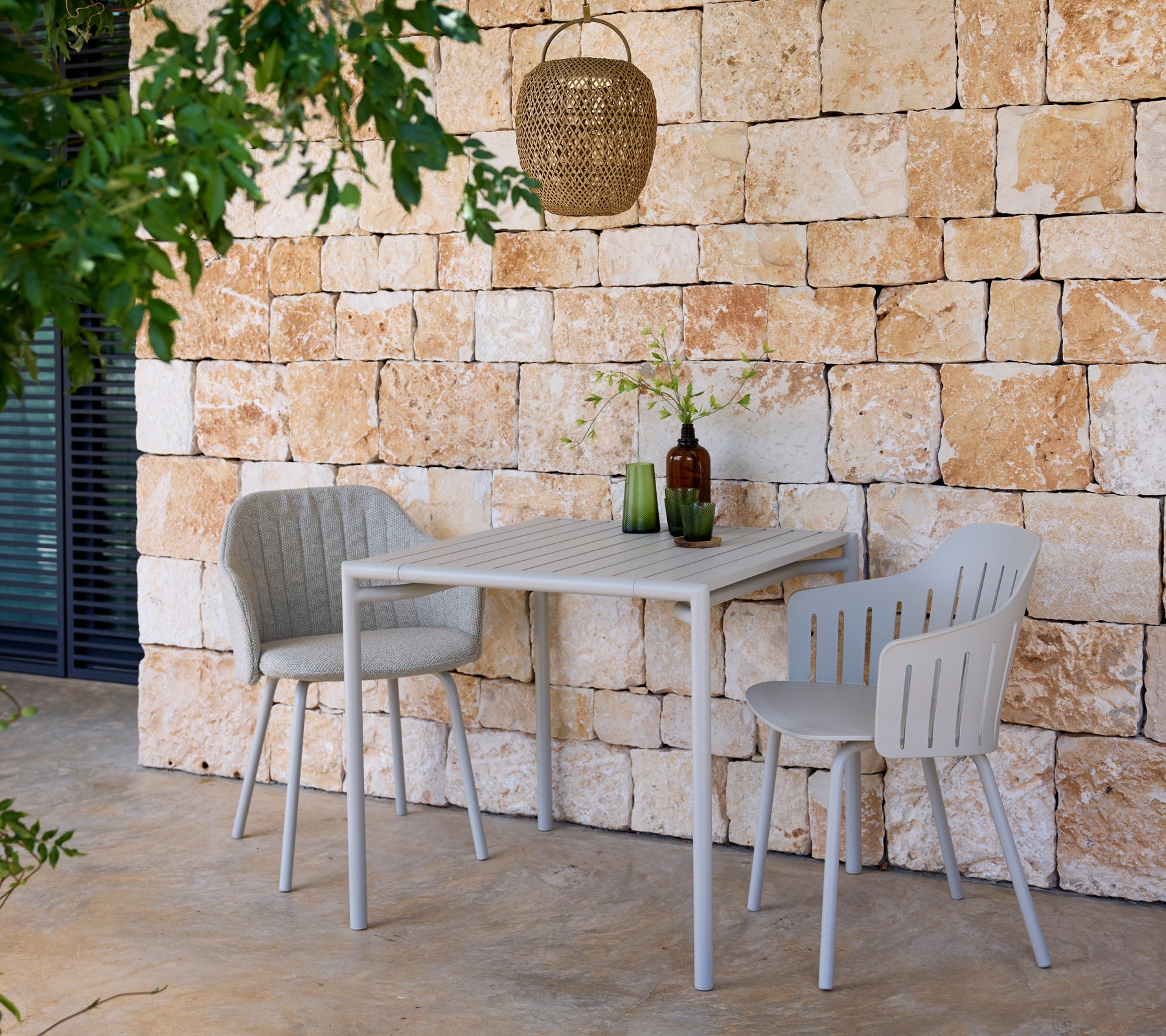 Modernem graues Tisch und Stühle mit grünen und braunen Flaschen in einer Außenumgebung.