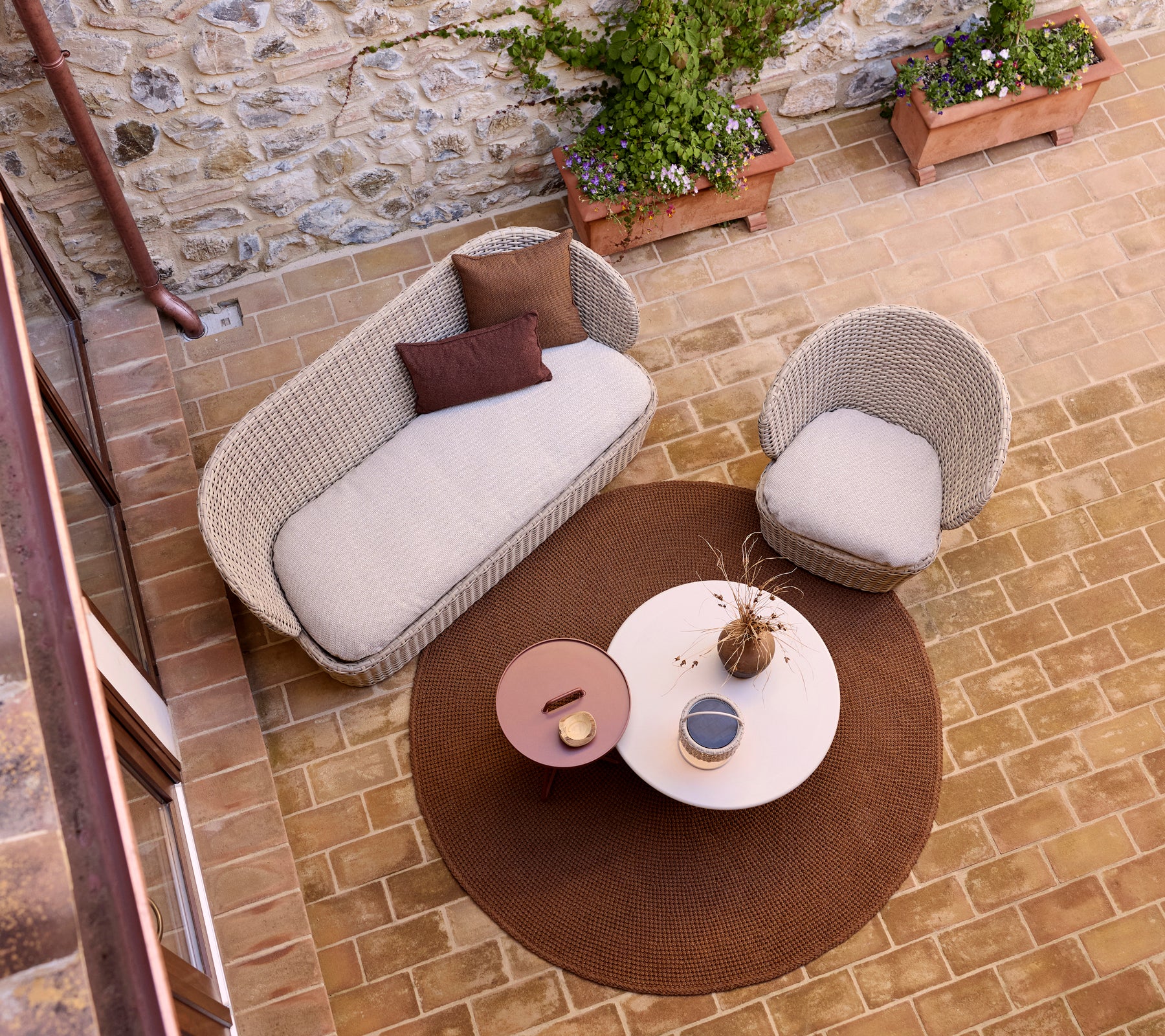 Gemütlicher Lounge-Bereich mit einem gestrickten Teppich, einem Glastisch und einer Illusionslampe, akzentuiert durch Topfpflanzen.