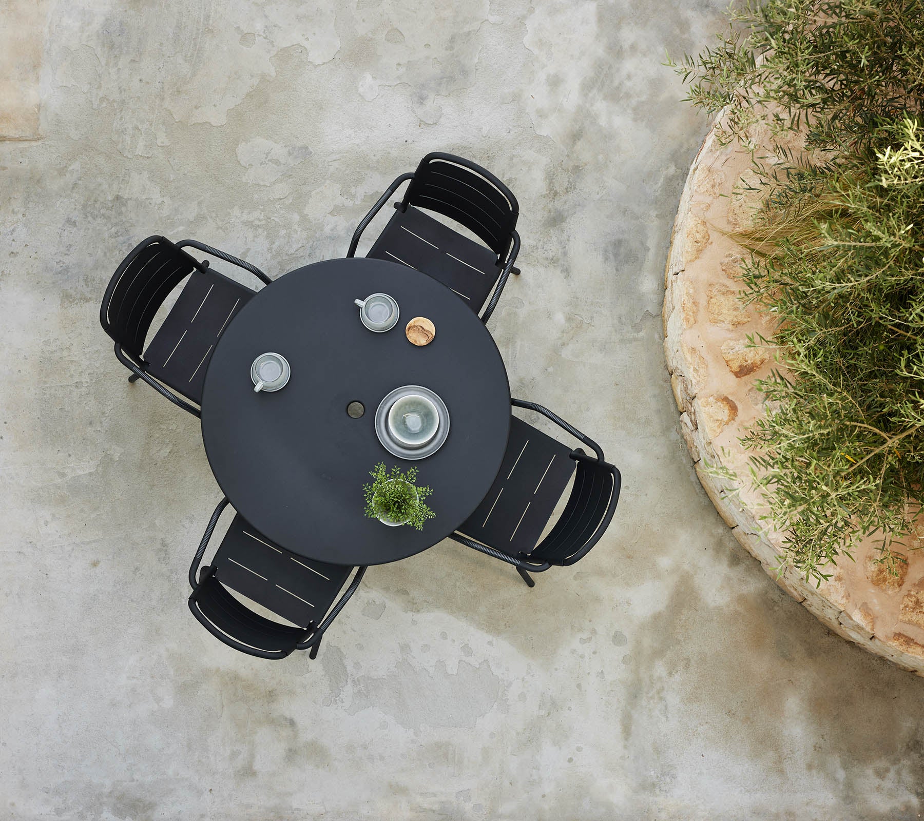 Eine Draufsicht auf einen runden Tischbereich, umgeben von Kopenhagener Stühlen, mit dekorativen Gegenständen und einer kleinen Pflanze.