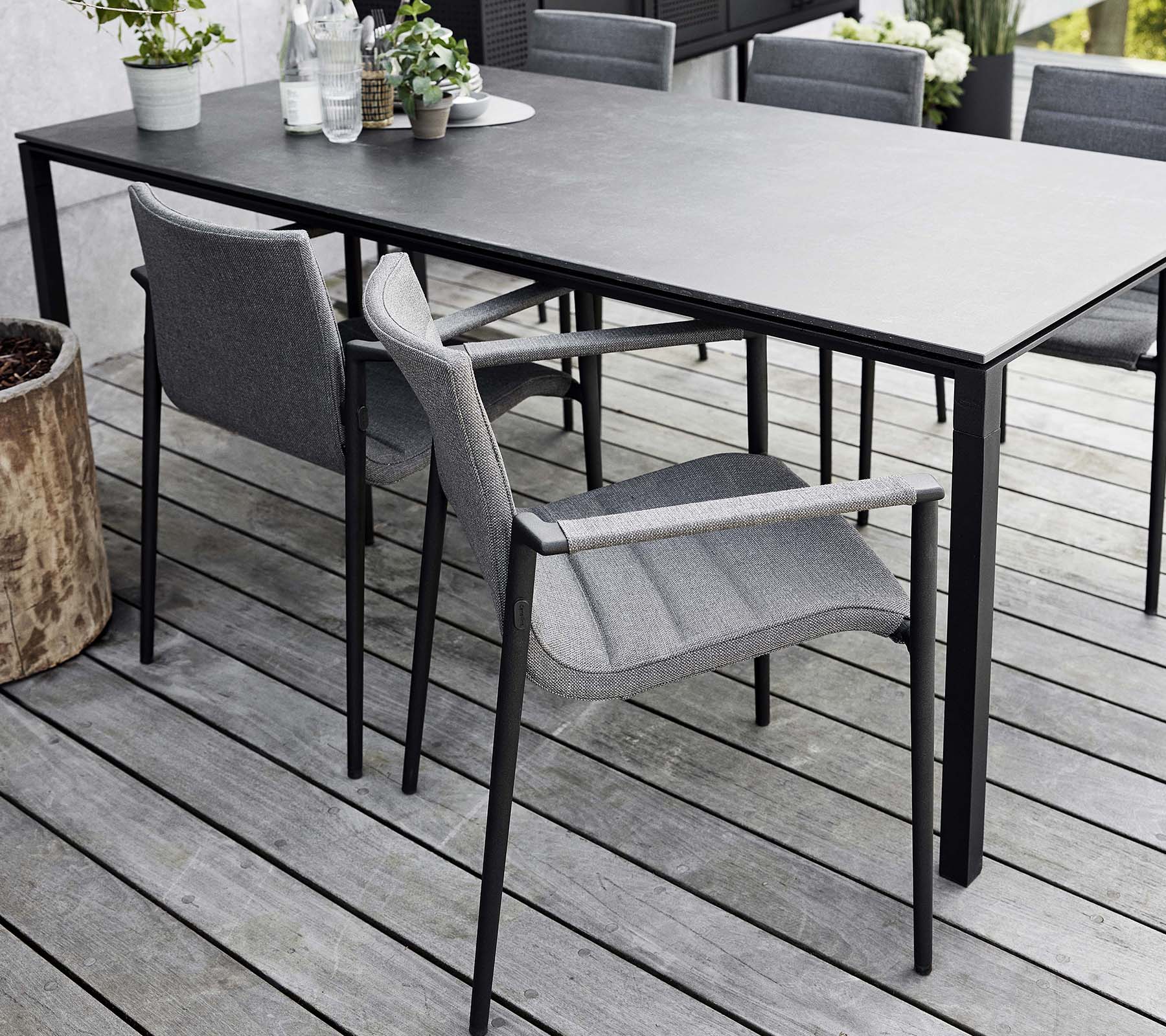 Stylisches Esssetup mit einem eleganten Tisch und modernen grauen Kernstühlen, umgeben von natürlichen Elementen und Grün.