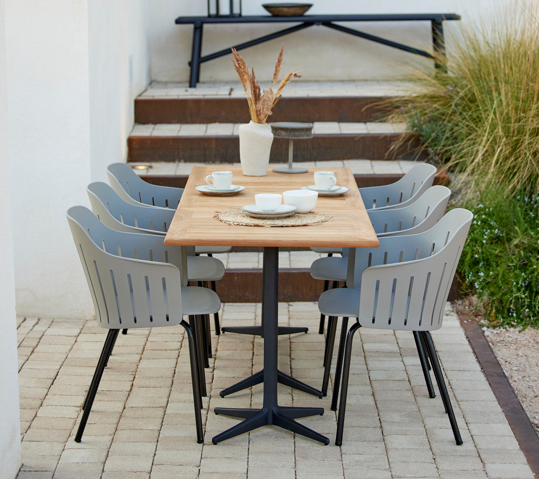 Ein stilvolles Essbereich mit einem Holztisch, umgeben von grauen Stühlen, ergänzt durch dekorative Elemente und Grünpflanzen.