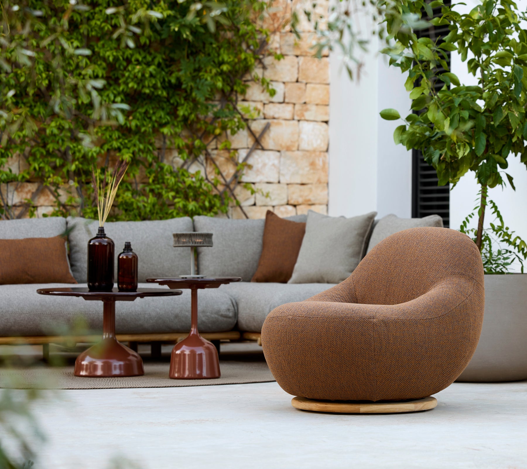 Modernes Lounge-Bereich mit einem braunen Sessel, einer grauen Couch und einem braunen Beistelltisch.
