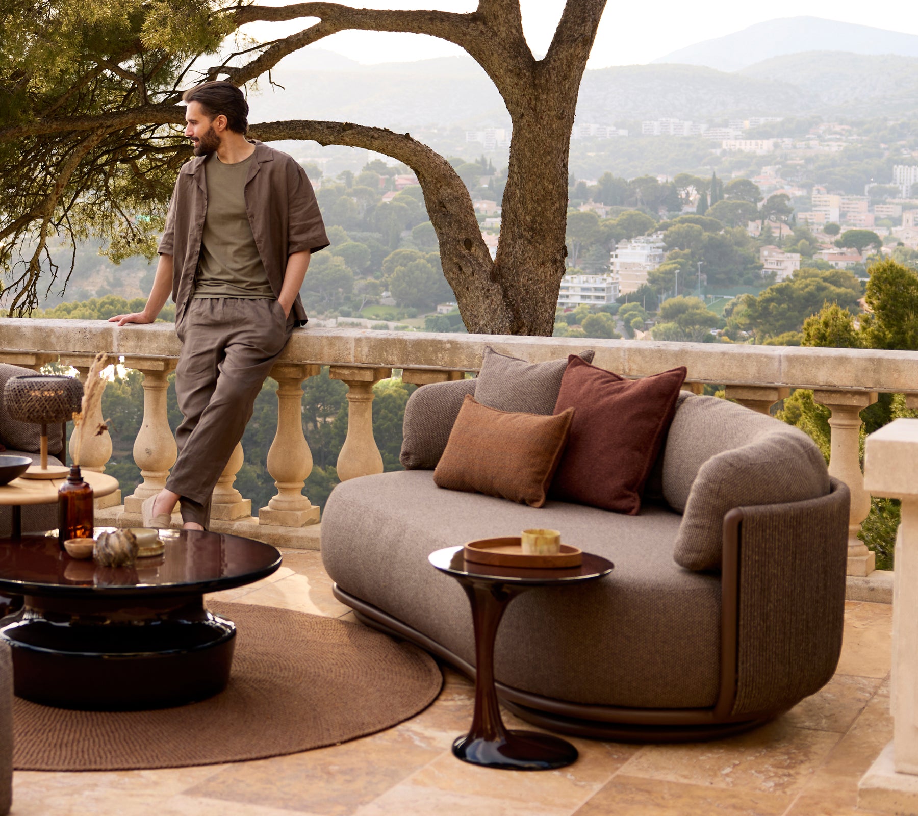 Graues Sofa mit braunen Kissen und einem schwarzen Couchtisch in einem modernen Lounge-Ambiente.