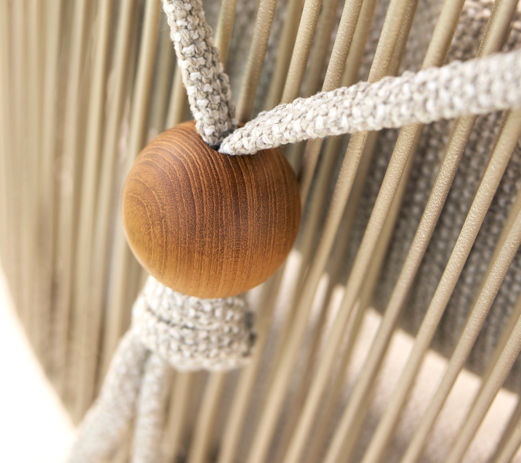 Nahaufnahme eines Nackenstützhalters für einen Hive-Stuhl, der eine Holzperle und gewebte Stoffriemen aufweist.