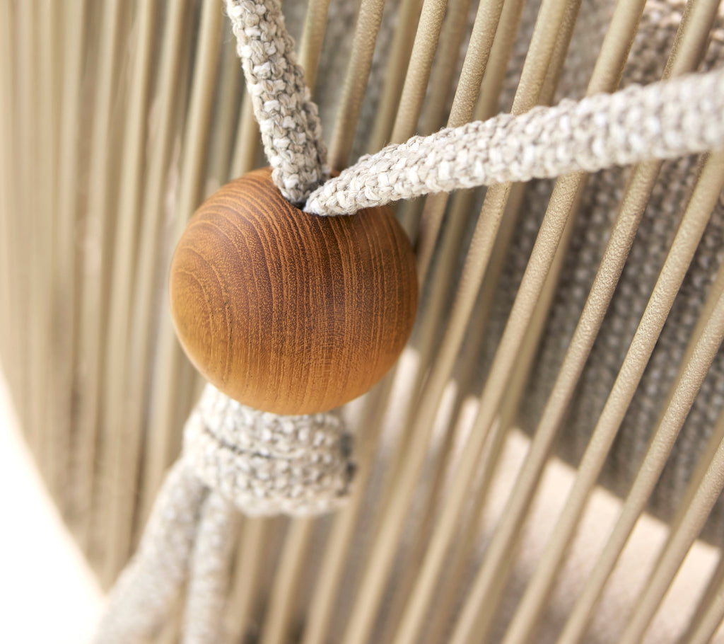 Nahaufnahme eines Nackenstützhalters für einen Hive-Stuhl, der eine Holzperle und gewebte Stoffriemen aufweist.