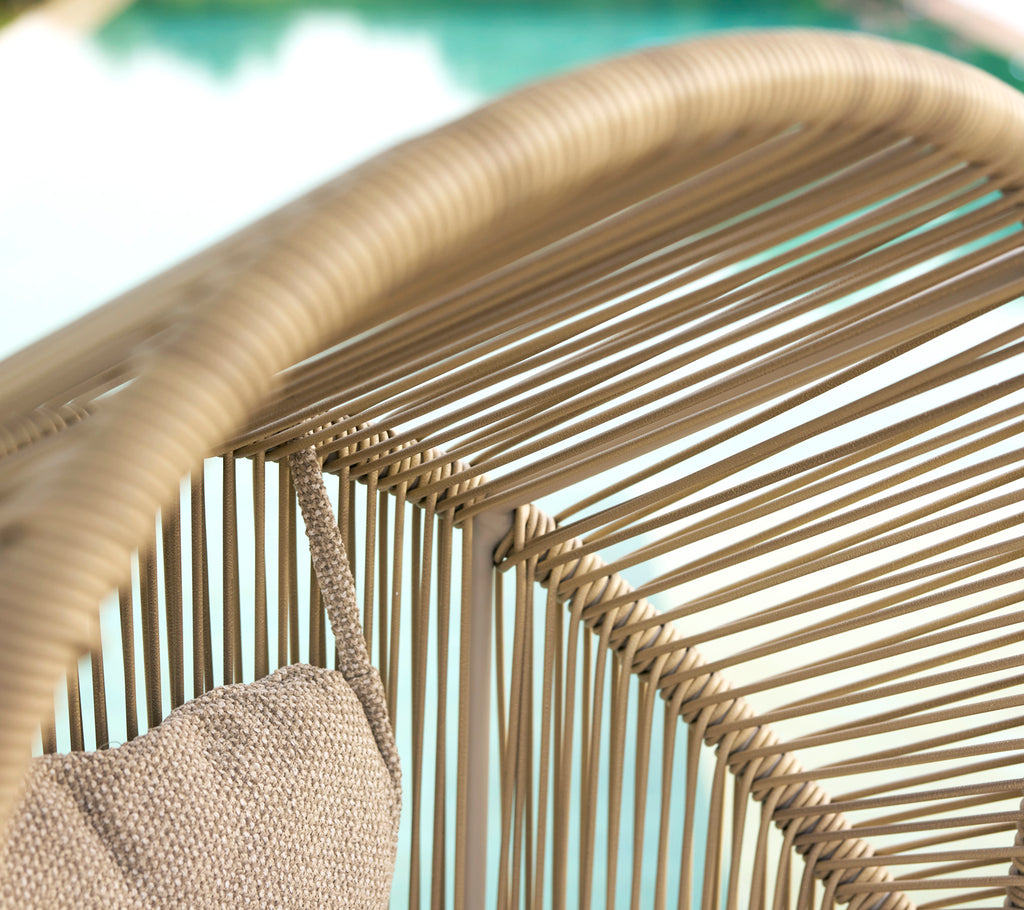 Nahaufnahme der Oberseite eines stilvollen Stuhls mit geflochtenen Strängen und einem gemütlichen Kissen für Komfort. Perfekt zum Entspannen.