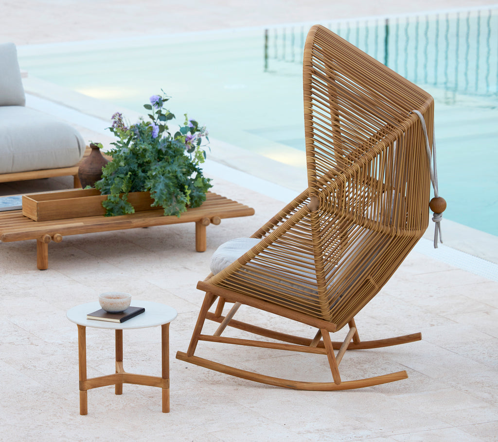 Ein stilvoller Hive Schaukelstuhl neben einem Twist-Couchtisch und einem Sticks-Couchtisch, ergänzt durch eine Topfpflanze.